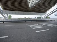 a street under a large bridge has white lettering on it with an open roof above it