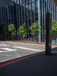 an empty street with several buildings in the background and some people crossing the sidewalk on bicycles