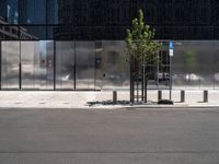 a parked car next to a tall grey building with some sort of wall and two trees in front of the building