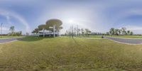 some very pretty architecture in the grass by the street as seen on a fisheye lens