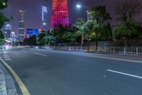 a city street with buildings and neon lights at night time in hong china as seen from an empty city highway