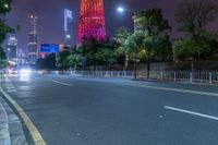 a city street with buildings and neon lights at night time in hong china as seen from an empty city highway