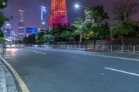 a city street with buildings and neon lights at night time in hong china as seen from an empty city highway