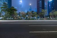 a city street with buildings and neon lights at night time in hong china as seen from an empty city highway