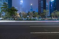 a city street with buildings and neon lights at night time in hong china as seen from an empty city highway