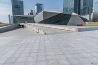 a skateboarder rides down a walkway in a city setting with many skyscrapers