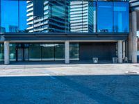 the shadow of a man sitting on a bench in front of an office building with a glass window