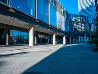 the shadows of buildings and trees are reflected on the windows of the building's glass wall