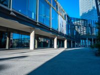 the shadows of buildings and trees are reflected on the windows of the building's glass wall