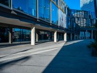 the shadows of buildings and trees are reflected on the windows of the building's glass wall