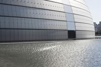 a person on a skateboard in front of a big building with a curved roof