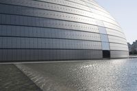 a person on a skateboard in front of a big building with a curved roof