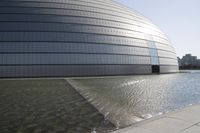 a person on a skateboard in front of a big building with a curved roof