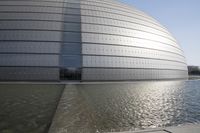 a person on a skateboard in front of a big building with a curved roof