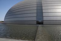 a person on a skateboard in front of a big building with a curved roof