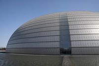 a person on a skateboard in front of a big building with a curved roof