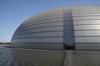 a person on a skateboard in front of a big building with a curved roof