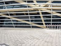 a bunch of poles in front of a very large building with some windows and a roof