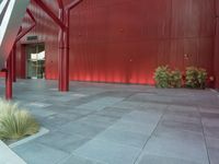 the metal poles hold up some red paint in front of the building with a long white stair