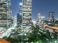 tall buildings in a city at night with street lights reflecting off the window windows and sky