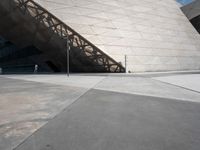 a man is walking outside near a large white structure in the daytime light with blue skies above