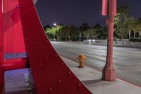 a brown fire hydrant standing next to a bridge at night with street and trees