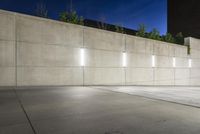 the large concrete wall has been illuminated by recessed lights at night on either side of it