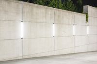 the large concrete wall has been illuminated by recessed lights at night on either side of it