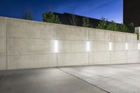 the large concrete wall has been illuminated by recessed lights at night on either side of it