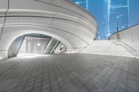 an open walkway leading up to a large building with two tall buildings in the distance