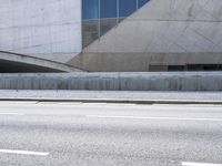 a man riding down an empty city street in front of large glass and concrete building