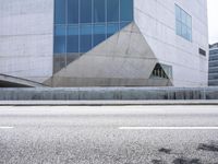 a man riding down an empty city street in front of large glass and concrete building