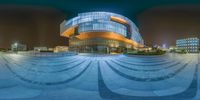 an outside shot of the building, with a curved path in front of it at night