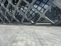 a man is standing in the foreground outside of a building that has curves of grey metal in it