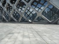 a man is standing in the foreground outside of a building that has curves of grey metal in it