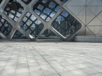 a man is standing in the foreground outside of a building that has curves of grey metal in it