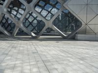 a man is standing in the foreground outside of a building that has curves of grey metal in it