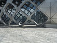 a man is standing in the foreground outside of a building that has curves of grey metal in it