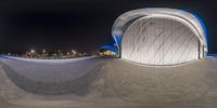 a skate boarder doing a trick in a skate park at night and another in the foreground