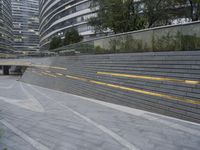 an urban area with stairs and a curved walkway with a bench and umbrellas on it