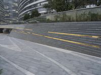 an urban area with stairs and a curved walkway with a bench and umbrellas on it