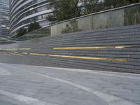 an urban area with stairs and a curved walkway with a bench and umbrellas on it