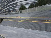 an urban area with stairs and a curved walkway with a bench and umbrellas on it