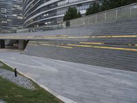 an urban area with stairs and a curved walkway with a bench and umbrellas on it