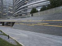 an urban area with stairs and a curved walkway with a bench and umbrellas on it