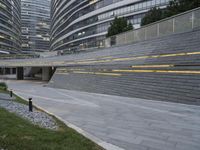 an urban area with stairs and a curved walkway with a bench and umbrellas on it
