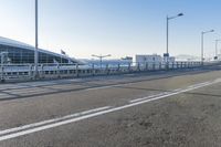 a car driving through an airport with white and blue stripes on the road, at the edge of a bridge