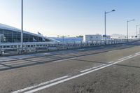 a car driving through an airport with white and blue stripes on the road, at the edge of a bridge