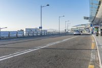 a car driving through an airport with white and blue stripes on the road, at the edge of a bridge