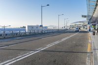 a car driving through an airport with white and blue stripes on the road, at the edge of a bridge